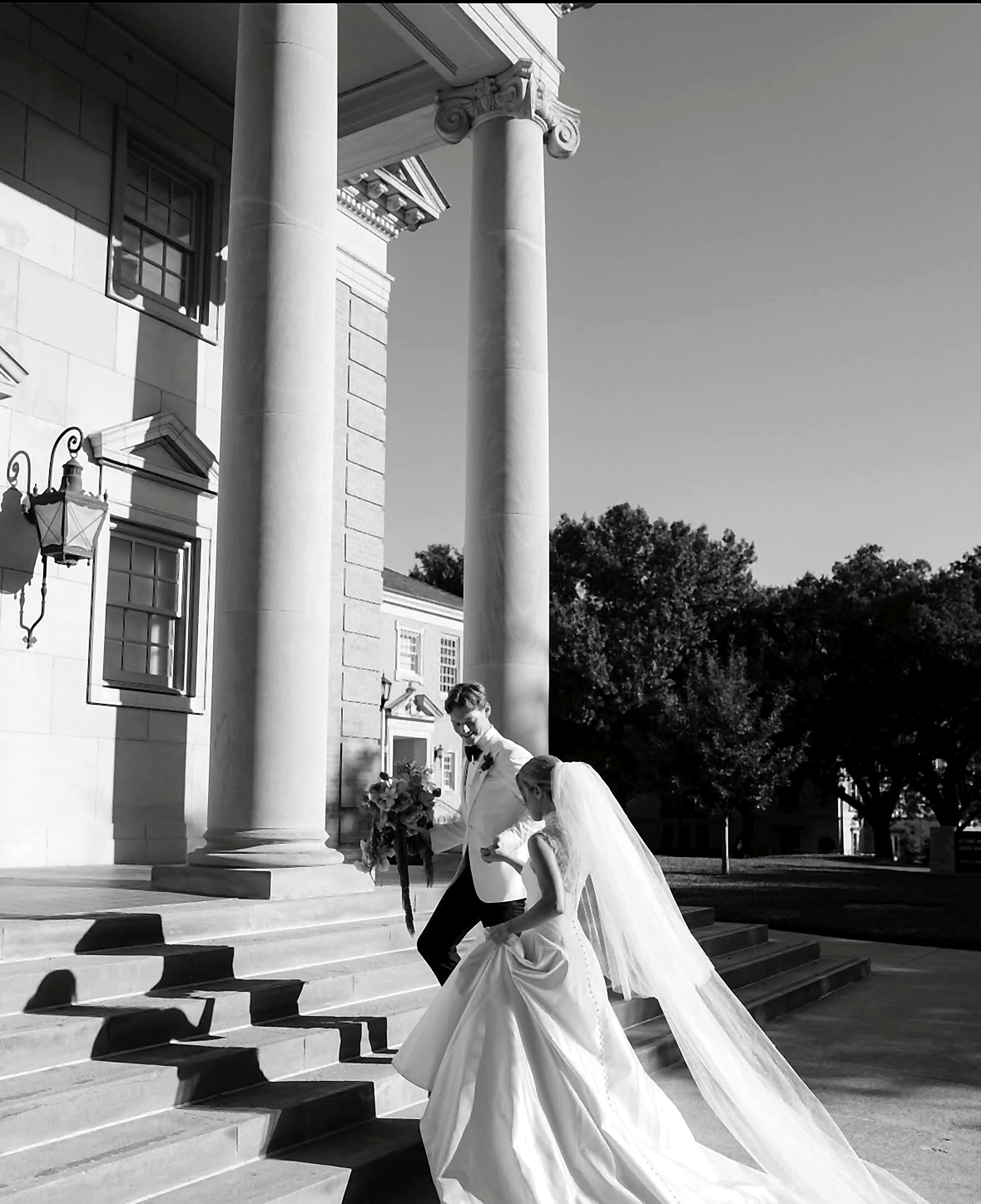 Black-and-white wedding portrait on grand steps.